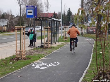 Droga rowerowa za przystankiem autobusowym.
