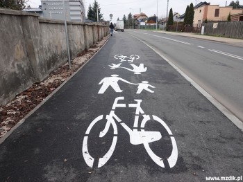 Ciąg pieszo-rowerowy obok muru cmentarnego.