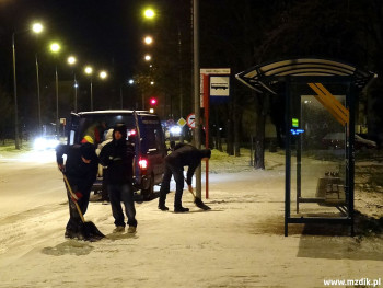 Nocne odśnieżanie przystanku autobusowego.